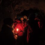 pupils in a dark cave lit by torch light
