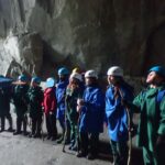 pupils wearing waterproofs and helmets getting instructions in a cave