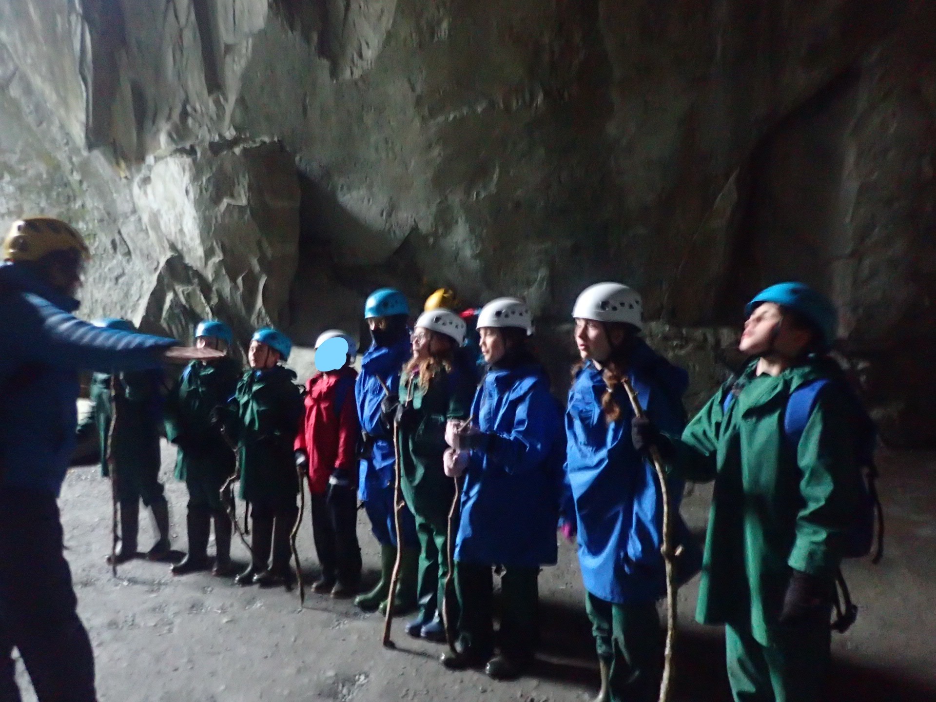 pupils wearing waterproofs and helmets getting instructions in a cave